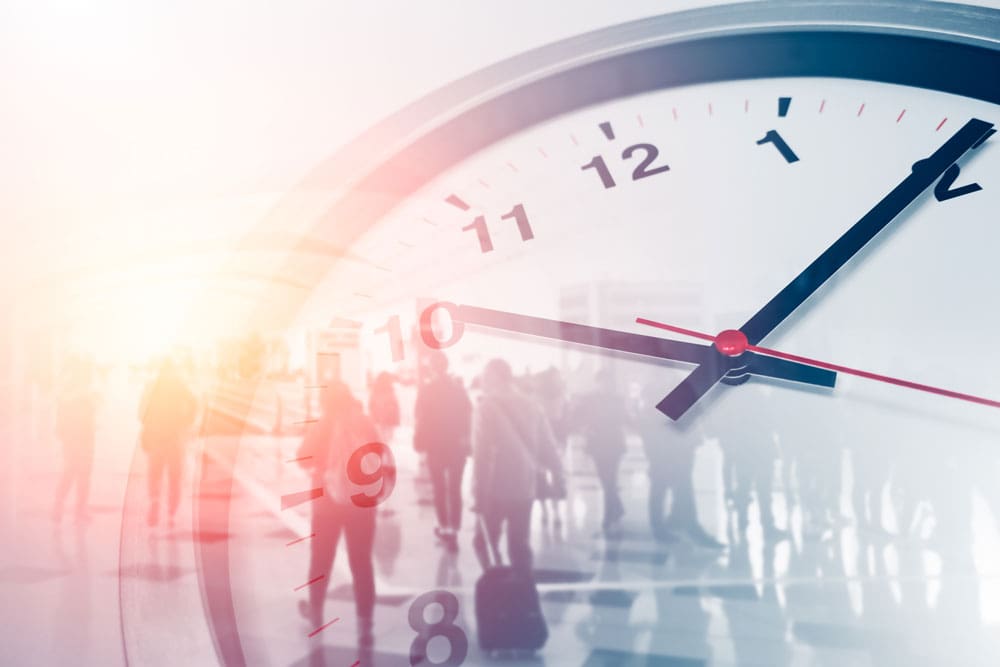 Eine Wanduhr, im Hintergrund sind Menschen zu erkennen